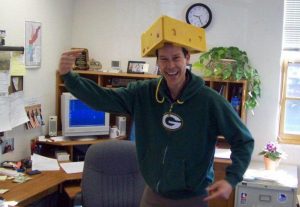 John O'Brien dons Green Bay Packers gear in the office Jan. 24 after losing a bet to an old friend. O’Brien, a die-hard Chicago Bears fan, bet Herb Tiffany, who loves the Green Bay Packers, if the Packers won he would wear their gear. If Chicago won, Tiffany would have to wear Bears gear.
