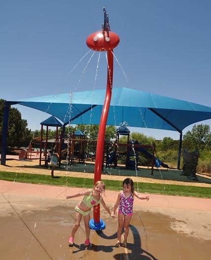 Kenzie Kykes, left, and Dalila Belle Mattheos stand under the spitting dragon at Sunset Park on Thursday, June 5, the opening day of the splash pad.