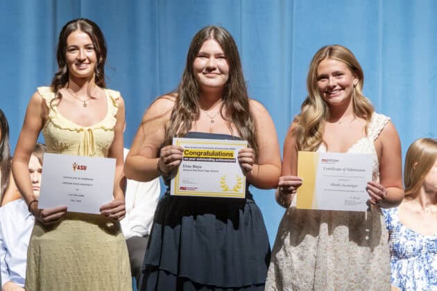 Graduation ceremony featuring students proudly holding diplomas and awards on stage.